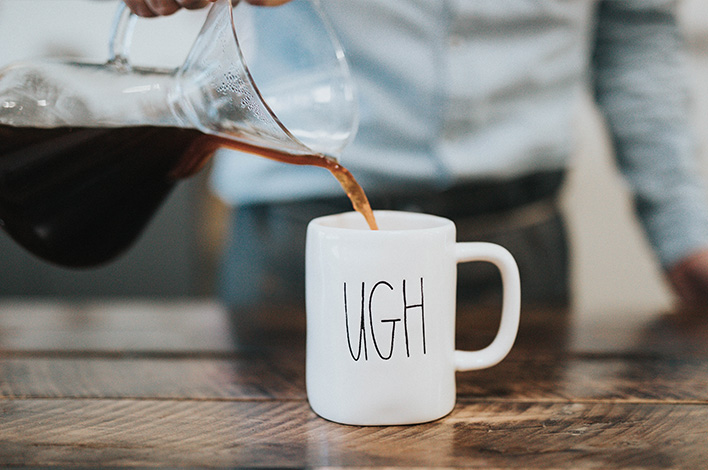 Pouring coffee into a mug that says ugh